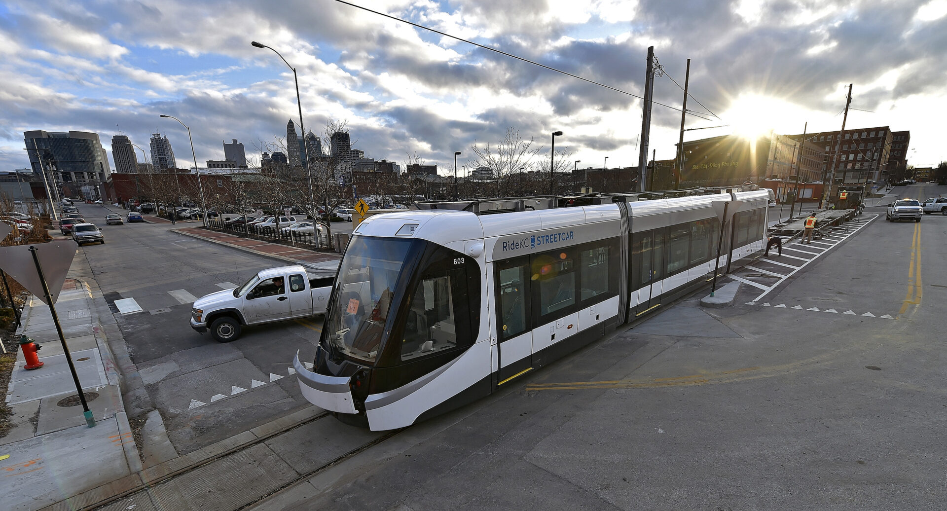 A white and black train on tracks near a street.